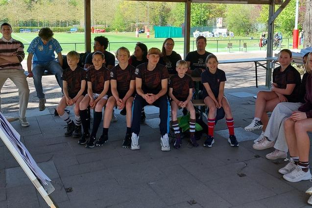 Jungs und M&auml;dchen des FC St. Pauli sitzen w&auml;hrend eines Lehrganges f&uuml;r Jungschiedsrichter und Jungschiedsrichterinnen auf B&auml;nken unter einem Carport vor einer Flipchart
