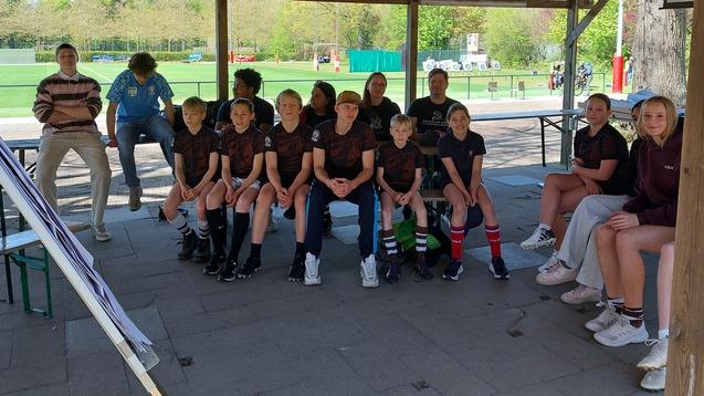 Jungs und M&auml;dchen des FC St. Pauli sitzen w&auml;hrend eines Lehrganges f&uuml;r Jungschiedsrichter und Jungschiedsrichterinnen auf B&auml;nken unter einem Carport vor einer Flipchart